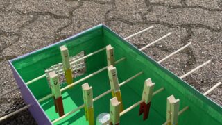Ein selbstgebastelter Tischkicker aus einem Schuhkarton und Wäscheklammern
