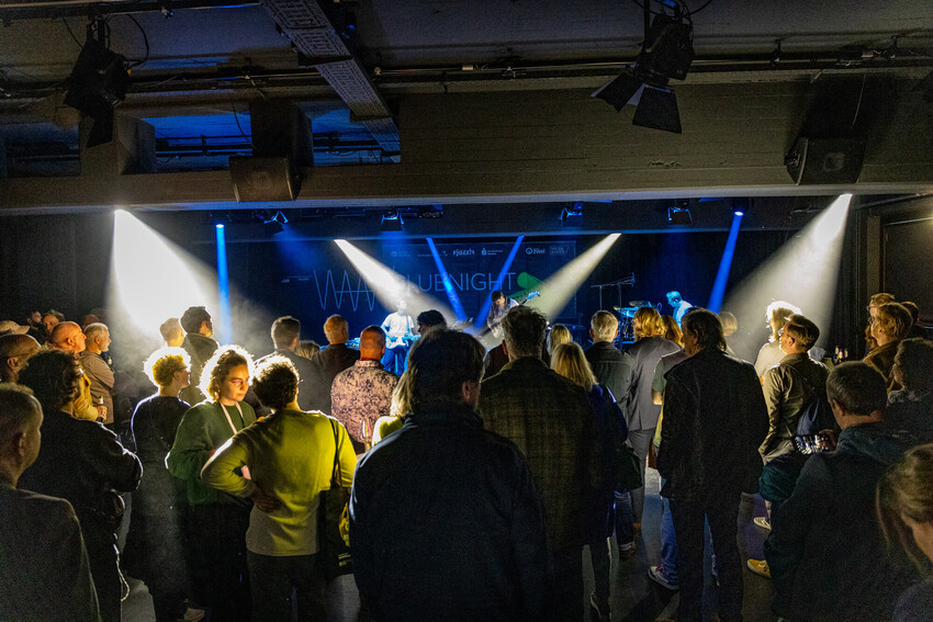 Besucherinnen und Besucher stehen dicht gedrängt vor einer Bühne während der jazzahead! CLUBNIGHT, während eine Band im Scheinwerferlicht spielt.