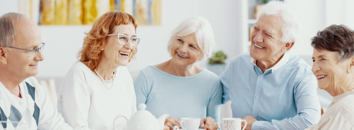 Gruppe älterer Menschen, die fröhlich an einer Kaffeetafel sitzen