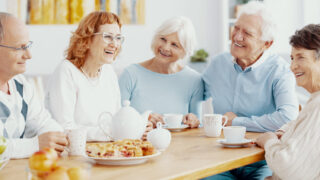 Gruppe älterer Menschen, die fröhlich an einer Kaffeetafel sitzen
