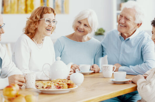 Gruppe älterer Menschen, die fröhlich an einer Kaffeetafel sitzen