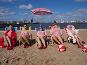 Fünf Frauen in Liegen im Badenixen-Outfit am Strand