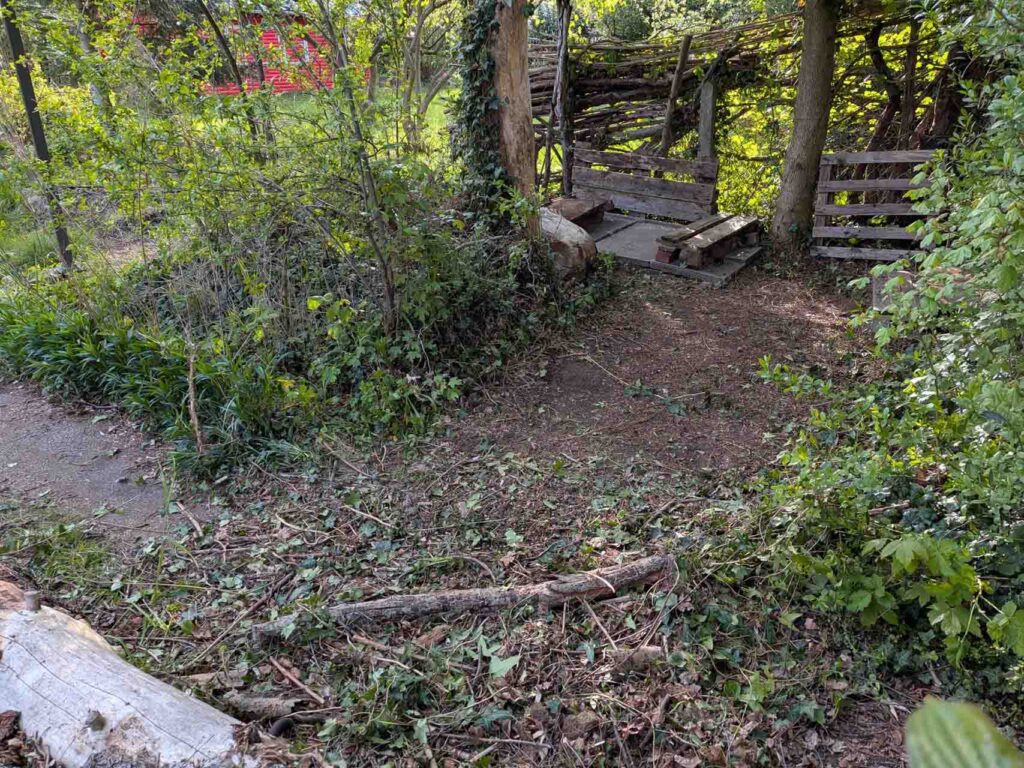 Naturnahe Sitzecke aus Holz zwischen Bäumen und Sträuchern im Klimagarten Findorff