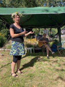Frau mit Blumenkranz spricht beim Sommerfest im Klimagarten Findorff