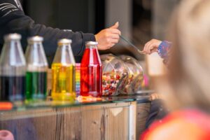 Bunte Limonadenflaschen und Süßigkeiten an einem Verkaufsstand.