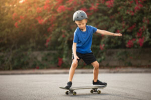 Ein Kind mit Helm fährt auf einem Skateboard und übt das Gleichgewicht.