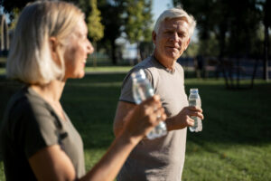 Zwei ältere Menschen trinken Wasser im Grünen