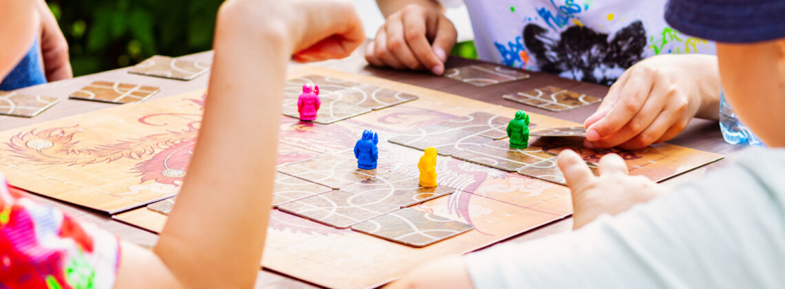 Kinder spielen gemeinsam ein Brettspiel mit bunten Spielfiguren.