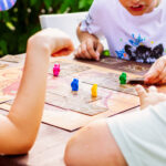 Kinder spielen gemeinsam ein Brettspiel mit bunten Spielfiguren.