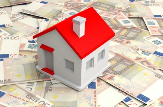 Das Foto zeigt ein Modellhaus mit rotem Dach, das auf einem Haufen 50 Euro Scheine steht. Symbolbild für: Finanzierung Immobilien Bremen