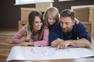 Eine Familie schaut lächelnd auf einen Bauplan - Symbolbild für Finanzierung Immobilien Bremen
