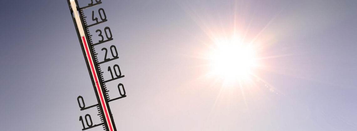 Thermometer vor strahlender Sonne zeigt hohe Temperaturen