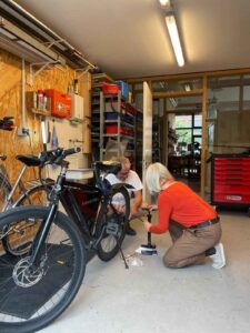 Zwei Personen reparieren gemeinsam ein Fahrrad in der Fahrradselbsthilfewerkstatt des Quartierstreffs Jetzt Hier.