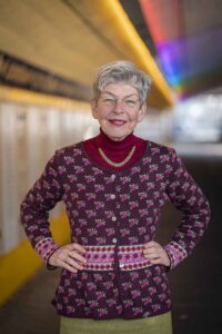 Regina Heygster steht lächelnd mit den Händen in den Hüften im farbig beleuchteten Bremer Friedenstunnel.