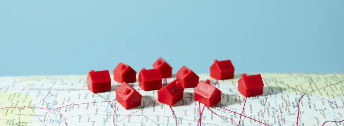 kleine rote Häuschen, die auf einer Landkarte stehen, Symbolbild für Immobilienmarkt