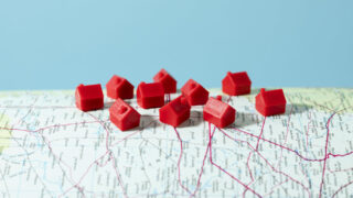 kleine rote Häuschen, die auf einer Landkarte stehen, Symbolbild für Immobilienmarkt