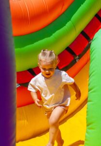 Kids Day Blumenthal: Nachdem das Kind von einer aufblasbaren hellen Rutsche auf ein Trampolin heruntergerollt ist, rennt es los, um zu spielen